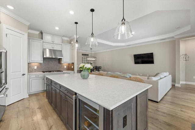 kitchen featuring gas cooktop, a tray ceiling, pendant lighting, a center island, and wine cooler