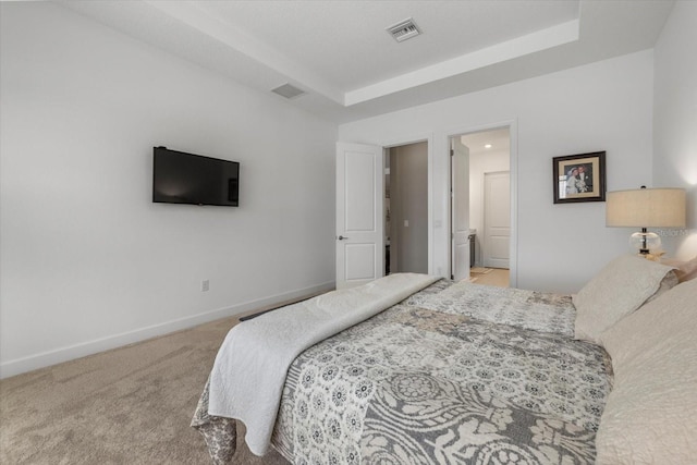 carpeted bedroom with a raised ceiling and ensuite bath