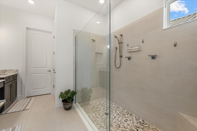 bathroom with a tile shower, vanity, and tile patterned floors