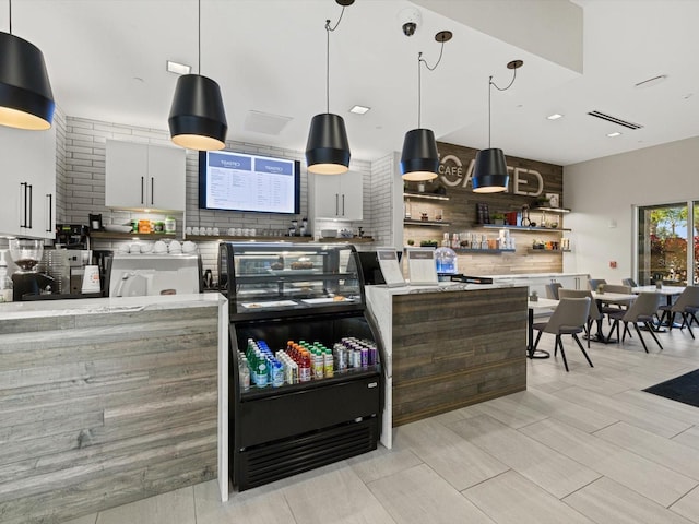 kitchen with decorative backsplash, pendant lighting, white cabinets, and light stone counters