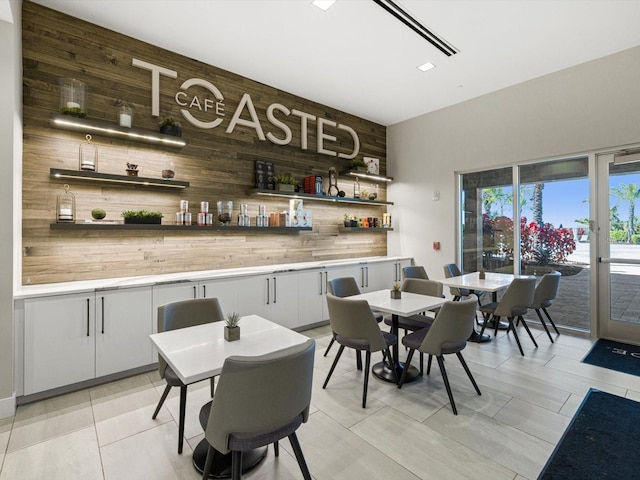 interior space featuring light tile patterned floors, white cabinetry, and wooden walls