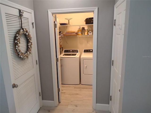 laundry room featuring separate washer and dryer and light hardwood / wood-style floors