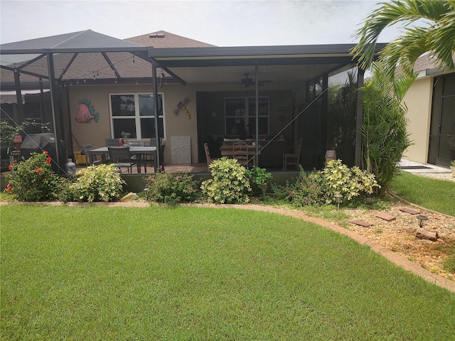 rear view of property featuring a patio, a yard, ceiling fan, and glass enclosure