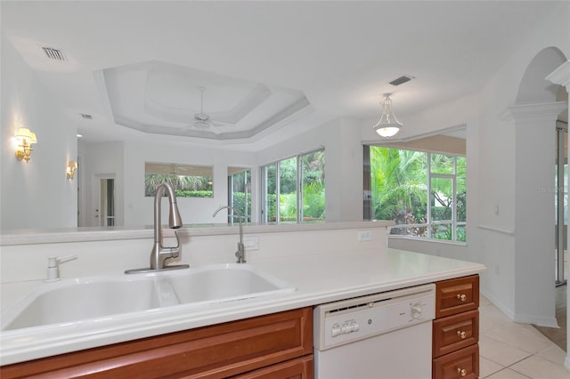 kitchen with visible vents, a tray ceiling, white dishwasher, a sink, and brown cabinets