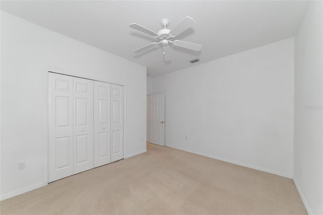 unfurnished bedroom featuring baseboards, visible vents, ceiling fan, a closet, and light carpet