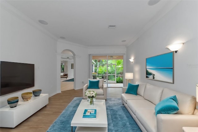 living room featuring visible vents, crown molding, baseboards, ceiling fan, and wood finished floors