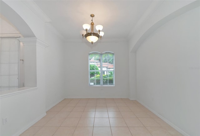 spare room featuring an inviting chandelier, light tile patterned floors, baseboards, and ornamental molding