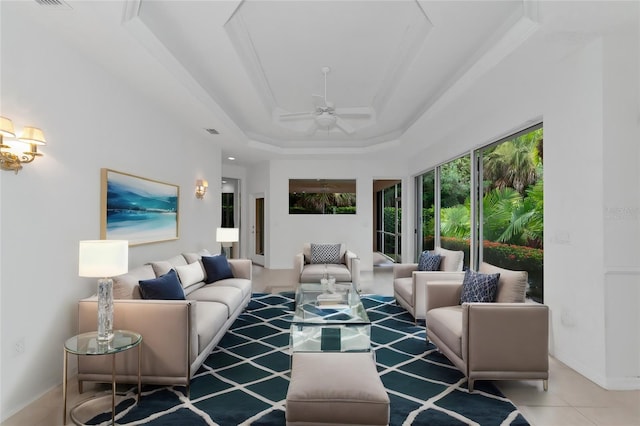 tiled living room with visible vents, baseboards, a raised ceiling, and ceiling fan