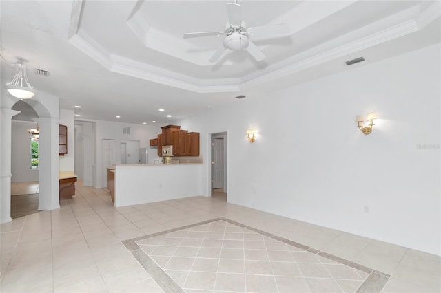 unfurnished living room with light tile patterned floors, visible vents, decorative columns, arched walkways, and a raised ceiling