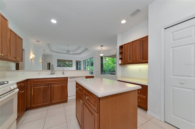 kitchen featuring visible vents, a peninsula, white appliances, a raised ceiling, and a sink