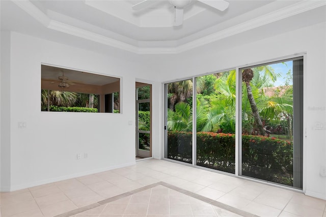 tiled empty room featuring a tray ceiling, baseboards, a wealth of natural light, and ceiling fan