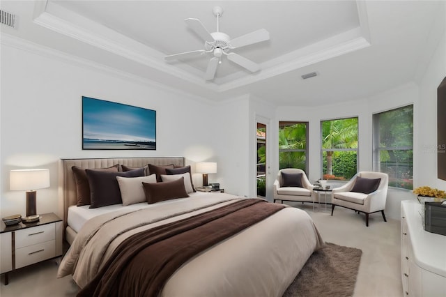 bedroom featuring light carpet, visible vents, a tray ceiling, and ornamental molding