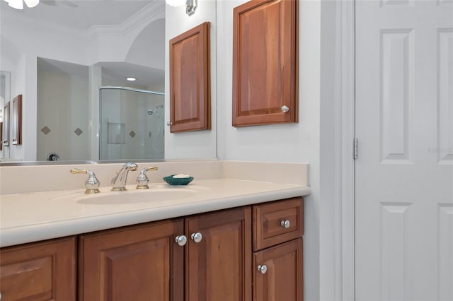 bathroom featuring vanity, a shower stall, and ornamental molding