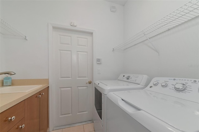 laundry room featuring washer and clothes dryer, light tile patterned flooring, and a sink