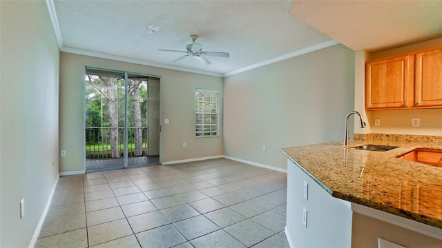 kitchen with ornamental molding, ceiling fan, sink, light tile patterned floors, and stone countertops