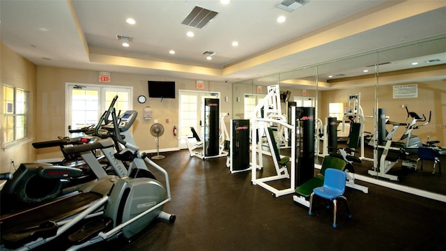 exercise room featuring a tray ceiling and french doors