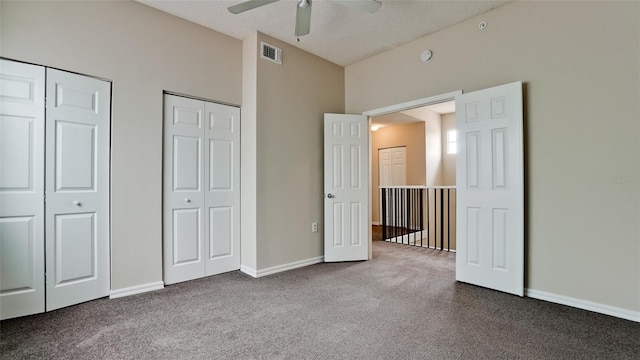 unfurnished bedroom with visible vents, baseboards, vaulted ceiling, multiple closets, and carpet