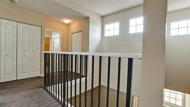 hall with a textured ceiling and carpet flooring