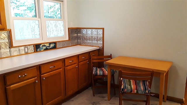 kitchen featuring brown cabinets, light colored carpet, and light countertops