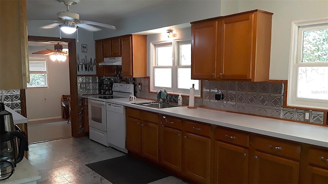 kitchen with brown cabinets, light countertops, a sink, white appliances, and under cabinet range hood