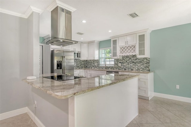 kitchen with appliances with stainless steel finishes, island range hood, white cabinets, decorative backsplash, and light stone counters