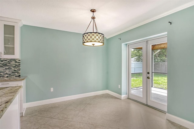 unfurnished dining area with french doors, crown molding, and light tile patterned floors