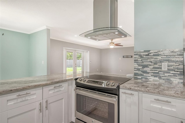 kitchen featuring french doors, light stone counters, stainless steel range with electric stovetop, island exhaust hood, and white cabinets