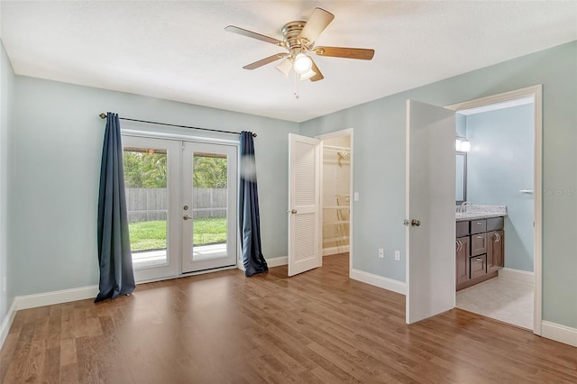 unfurnished bedroom featuring french doors, ensuite bath, light hardwood / wood-style flooring, and access to outside