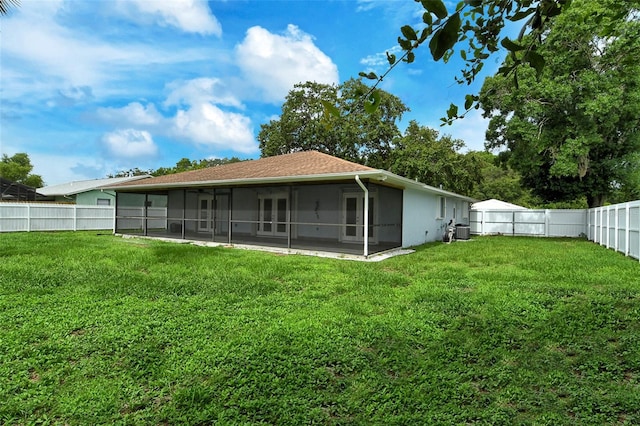 rear view of property featuring a lawn, a sunroom, and a patio