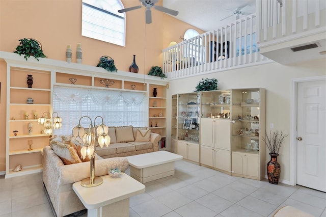 living room featuring a towering ceiling, light tile patterned floors, and ceiling fan