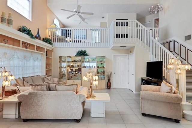 tiled living room with ceiling fan with notable chandelier and high vaulted ceiling