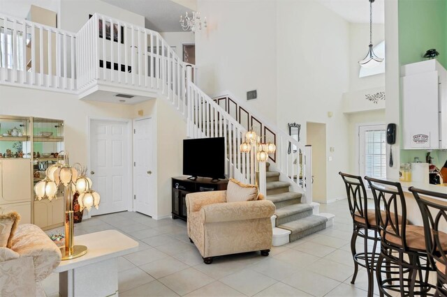 living room featuring light tile patterned flooring, a towering ceiling, and a chandelier