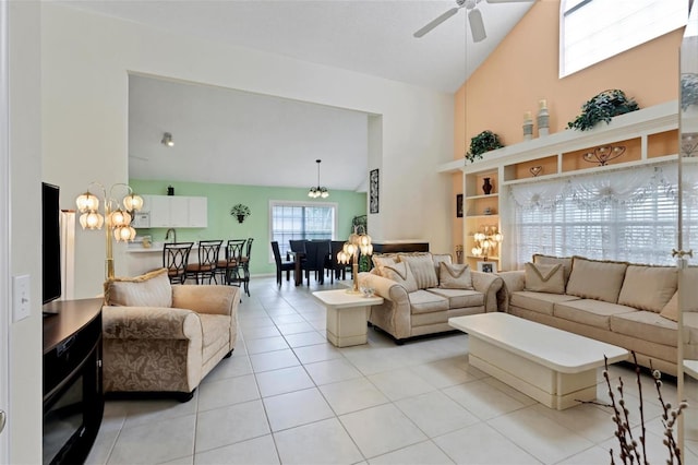 living room featuring light tile patterned flooring, ceiling fan with notable chandelier, and high vaulted ceiling