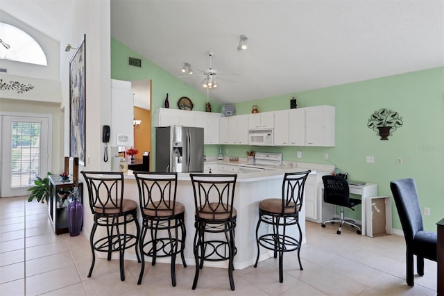 kitchen featuring light tile patterned flooring, kitchen peninsula, and white appliances