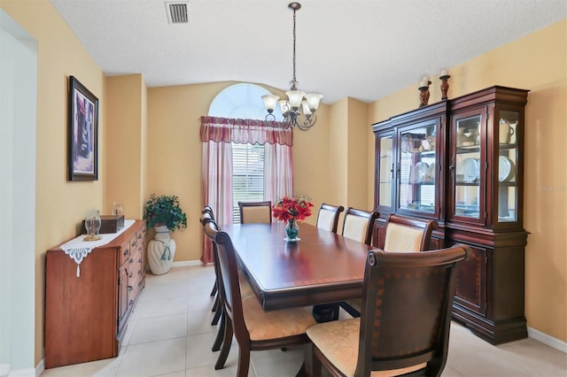 tiled dining area featuring a notable chandelier and a textured ceiling