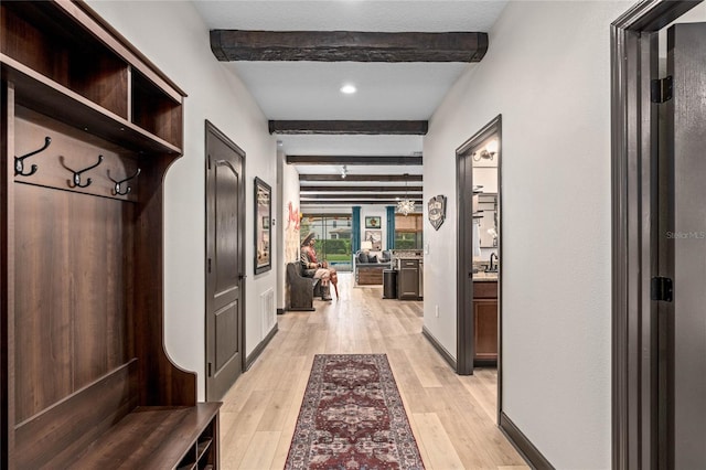 mudroom featuring beamed ceiling and light hardwood / wood-style floors