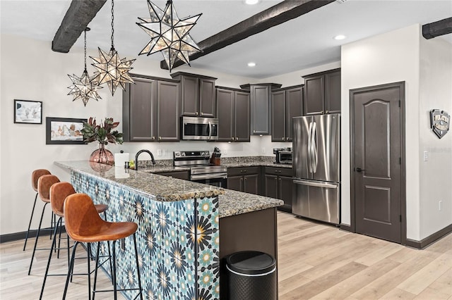 kitchen with beamed ceiling, decorative light fixtures, and appliances with stainless steel finishes