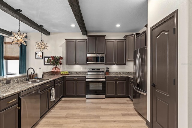 kitchen with appliances with stainless steel finishes, beamed ceiling, light hardwood / wood-style flooring, sink, and pendant lighting