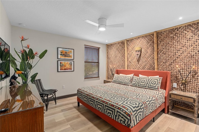 bedroom with a textured ceiling, ceiling fan, and hardwood / wood-style floors