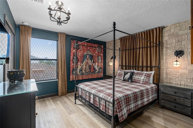 bedroom with light hardwood / wood-style floors, a notable chandelier, and a textured ceiling