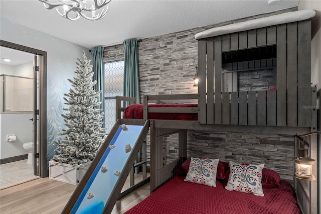 bedroom featuring hardwood / wood-style flooring, a notable chandelier, ensuite bath, and a textured ceiling