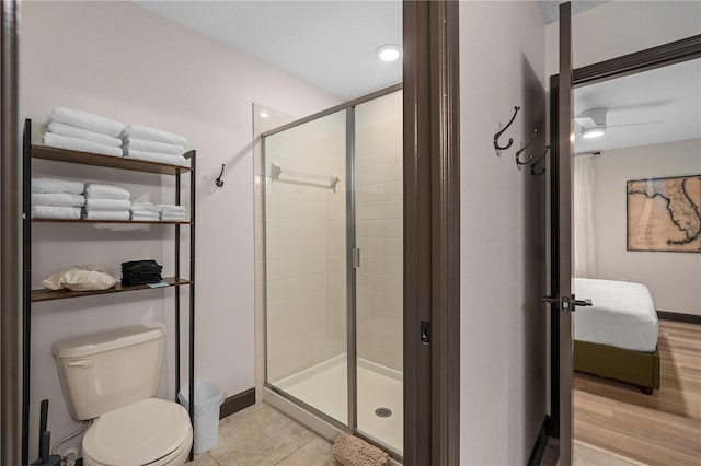 bathroom with a shower with door, ceiling fan, hardwood / wood-style flooring, and toilet