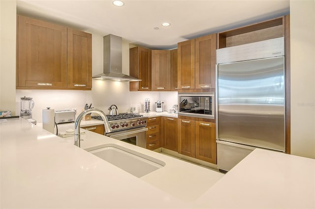 915 Seaside Drive 607, Weeks 14-15, Sarasota, FL 34242 - kitchen with built in appliances, wall chimney range hood, light countertops, recessed lighting, and brown cabinets