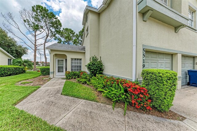 doorway to property with a garage and a yard