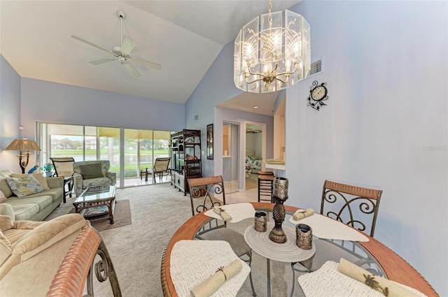 carpeted dining area featuring ceiling fan with notable chandelier and high vaulted ceiling