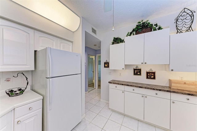 kitchen featuring white cabinetry, white fridge, light tile patterned floors, and a textured ceiling