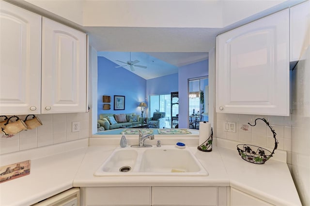 kitchen featuring lofted ceiling, sink, dishwashing machine, ceiling fan, and white cabinets