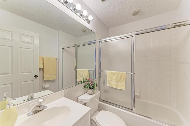 full bathroom with vanity, toilet, combined bath / shower with glass door, and a textured ceiling