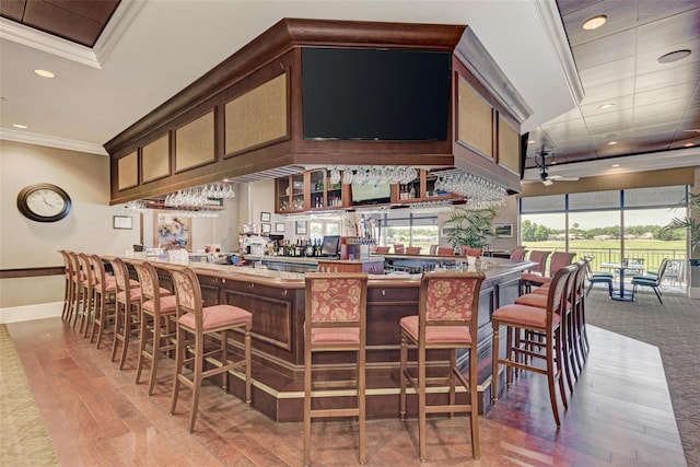 bar with ornamental molding, wood-type flooring, and ceiling fan