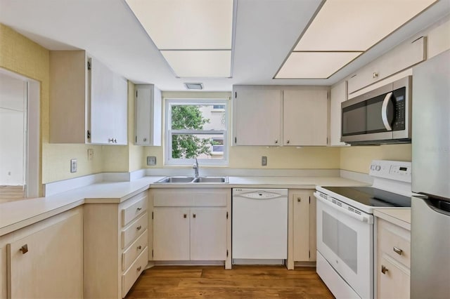 kitchen with cream cabinets, sink, appliances with stainless steel finishes, and light hardwood / wood-style flooring